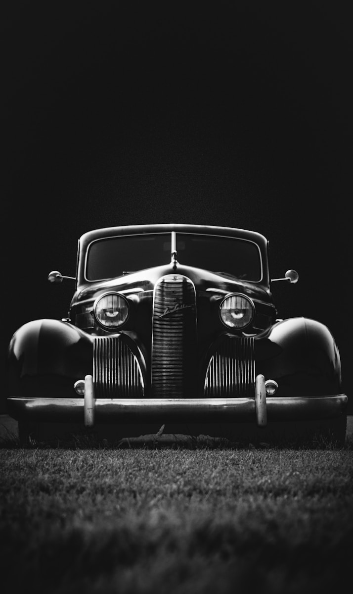 greyscale photo of classic vehicle with automobile insurance on ground