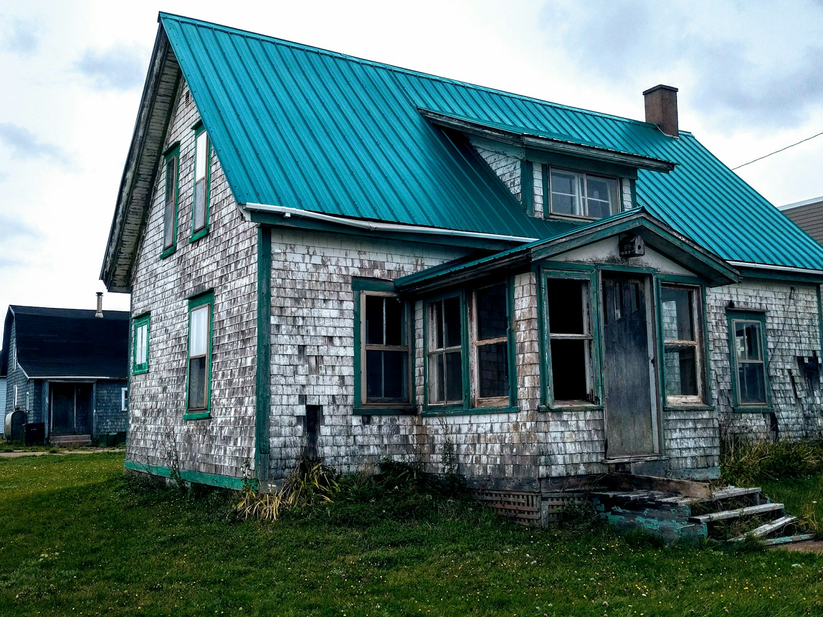 white brick house with green roof with homeowners insurance